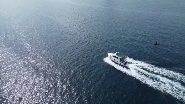 White big boat motion on blue water aerial view. Flight over a white yacht in motion alt