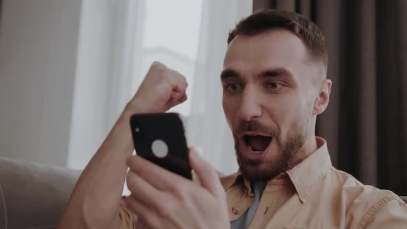 Happy Young Handsome Man Holding Mobile Phone Feeling Excited of Getting Sms with Pleasant News alt