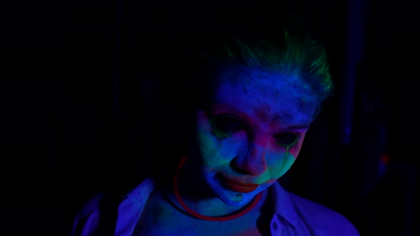 Horror Movie Concept Portrait of Woman with Flourescent Paints on Face in Darkness alt