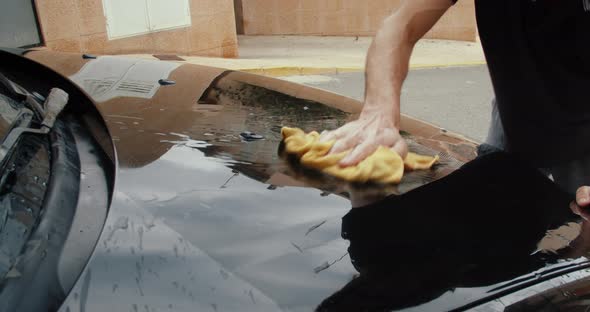 Close Up Slender Man in Dark Tshirt Washes Black Car with Rag and Lots of Water alt