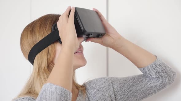 Blonde woman slow motion in white space trying virtual reality glasses  1080p HD footage - Blond fem alt