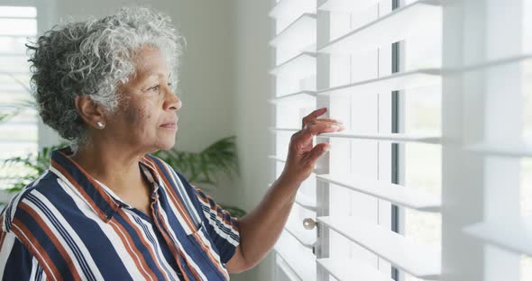 Animation of serious african american senior woman looking outside window alt