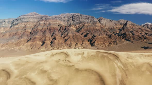 People Hiking to the Top of High Sand Dune with Painted Mountains Landscape alt