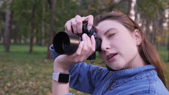A Woman Takes Pictures on a Black Compact Camera Against the Background of a Beautiful Autumn Park