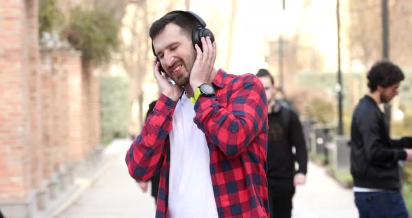 Young stylish man in headphones walking the city street. alt