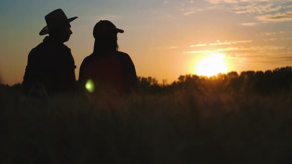 Silhouette Farmers Talking in a Wheat Field Against Sunset alt