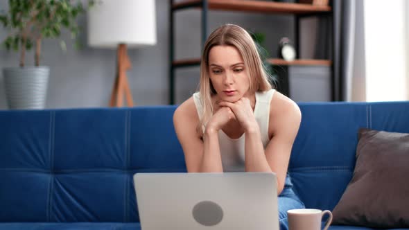 Pensive Blonde Woman Thinking Worried About Problem Sitting on Couch in Front of Laptop Pc at Home alt
