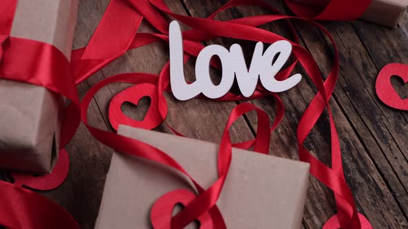 Rotating Valentine's Day Background with Boxes Gifts Red Ribbons and Hearts and the Inscription Love