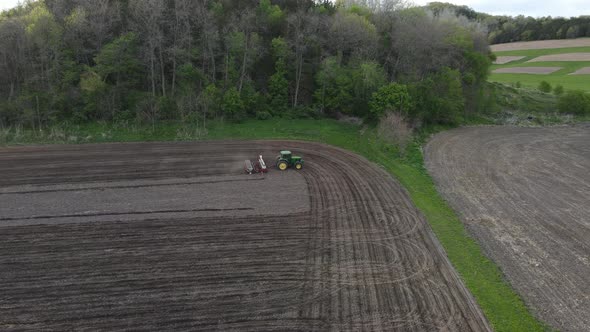 Aerial view of farmer fertilizing and planting the last rows in section of field late in day.