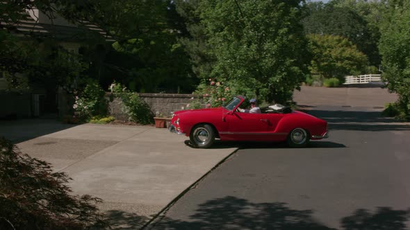 Tracking shot of man pulling out of driveway in classic convertible car.  Fully released for commerc