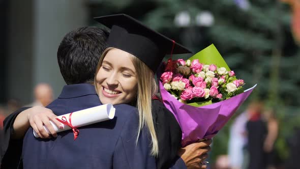 Happy Female Embracing Warmly Man With Bunch of Flowers, Graduation Ceremony alt
