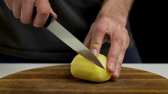 Chef cutting and slicing peeled potato on chopping board, closeup alt