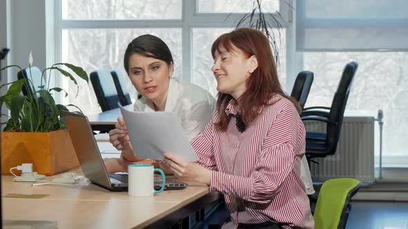 Two Businesswomen Doing Paperwork Together at the Office alt