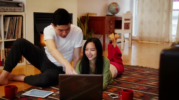 Couple using laptop in living room alt