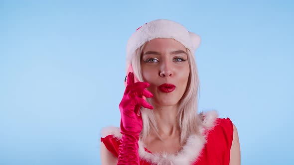 Cute Young Woman Dressed As Santa Claus Is Talking on a Cell Phone