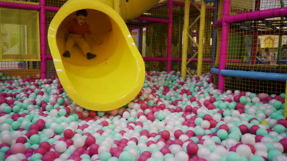 A Fiveyearold Boy Rolls Down a Tube Slide and Falls Into Inflatable Balloons