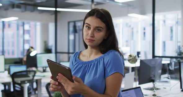 Portrait of caucasian businesswoman standing in office holding tablet and smiling to camera alt