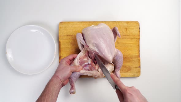 Male Hands Butcher Carcass of Raw Chicken on a Wooden Cutting Board alt