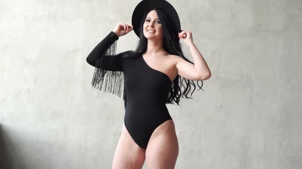 Sexy Woman in a Black Bodysuit and Hat at the Gray Wall alt