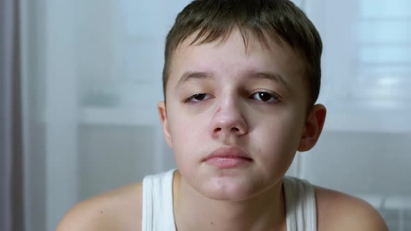 Face Portrait of a Serious Teenager Sitting in a Room Looking Away alt