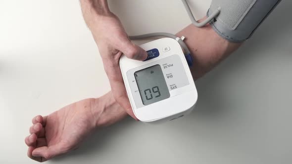 Man's Hand and Tonometer on White Table for Measuring Blood Pressure