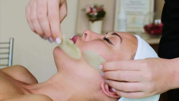 Facial Massage with Slices of Stones for Young Woman in Beauty Spa Salon alt