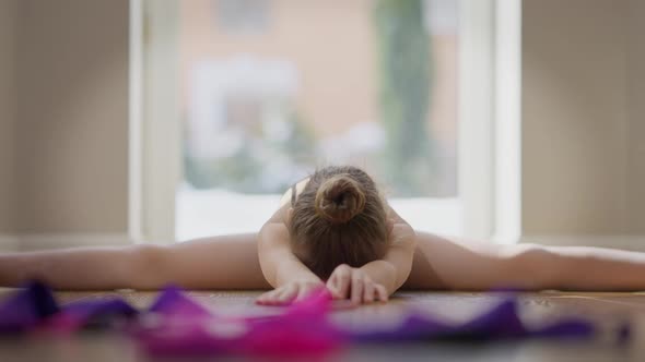 Motivated Confident Teen Gymnast Looking at Camera Stretching Muscles Sitting on Twine alt