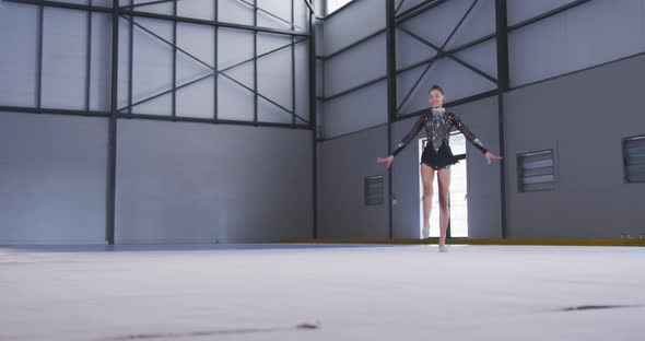 Teenage female gymnast performing at sports hall alt