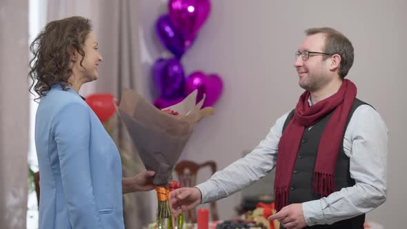 Side View Portrait of Smiling Man Giving Bouquet of Flowers to Woman and Thankful Wife Hugging alt