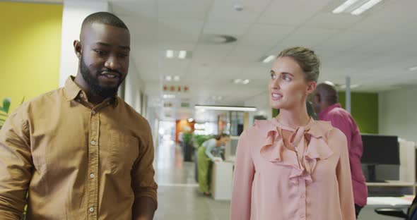 Diverse male and female business colleagues talking and walking in office alt