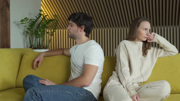 Young Couple Experiencing Relationship Problems Is Sitting Next To Each Other at Home on a Yellow alt