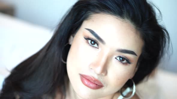 Portrait of Sexy Asian Female Beauty Model Posing Sensually to Camera in Bed alt