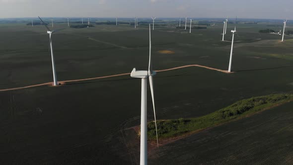 Drone orbiting around a windmill turbine in a green field of beans in the midwest alt