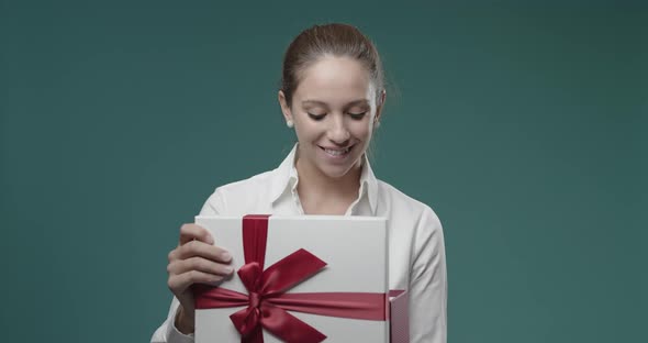 Happy young woman opening a gift box, Christmas and celebrations concept