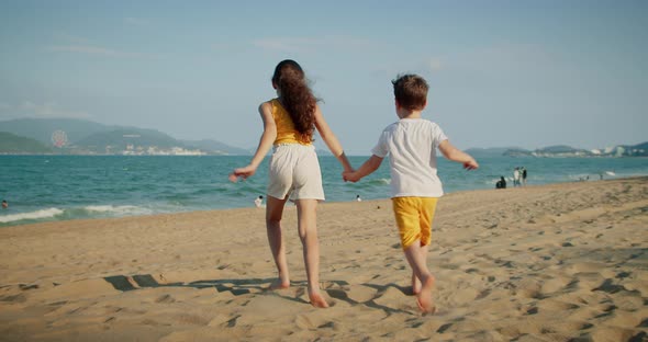 Happy Young Kids Running Down Beach Playing with Their Dog Family Beach Vacation alt
