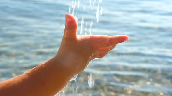 Baby's Hand Catching Water Drops on Seascape Background