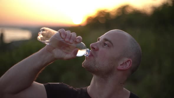 Closeup Slow Motion Side View of Caucasian Bald Muscular Guy Wearing Black Tshirt Drinking Water alt