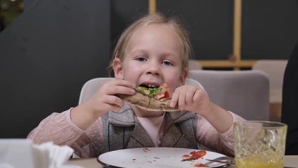 Closeup of Charming Little Girl Biting and Chewing Pizza in Restaurant alt