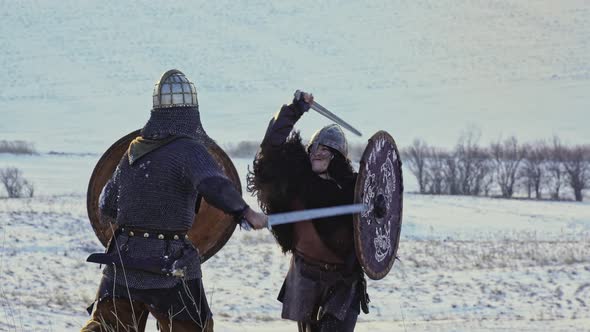 Two Viking Are Fighting with Axes and Shields on the Winter Meadow