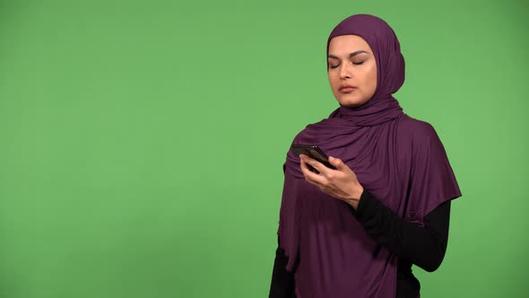 A Young Beautiful Muslim Woman Works on a Smartphone and Acts Upset  Green Screen Background