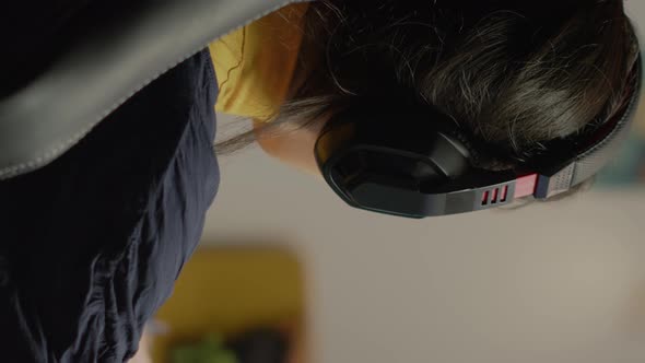 Vertical Video Focused Woman Gamer Sitting on Desk Putting on Headset alt