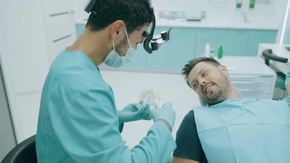 Doctor Dentist Is Showing To Happy Patient on a Jaw Model How To Clean the Teeth with Toothbrush