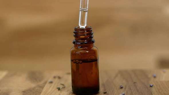 A woman picks up a jar of lavender essential oil. Close-up of extract Lavender Oil. alt