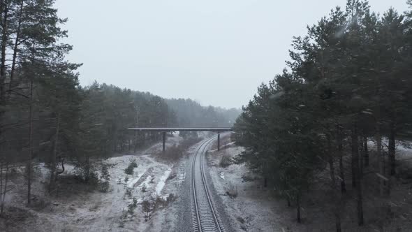 AERIAL: Railway with Overpass Bridge in the Distance on a Snowstorm