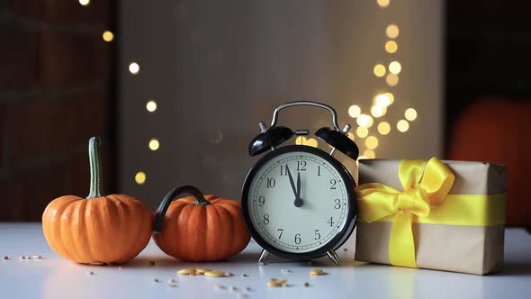 Vintage black alarm clock on a table with gift and pumpkin