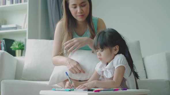 Home study concept : A Beautiful single Asian mother teaching her daughter to read, write and drawin alt