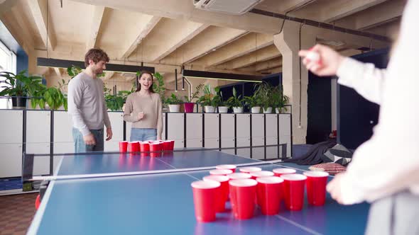 Group of Young People Playing Beer Pong in a Large Room alt