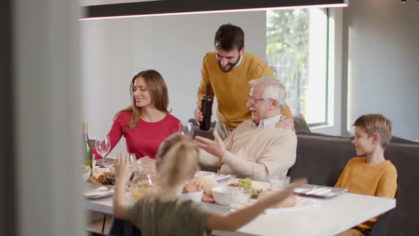 Happy family having a dinner with red wine at home