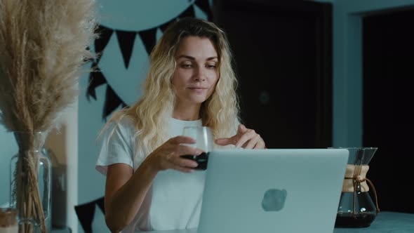Pretty blonde woman enjoying taste and smell of Americano in a coffee shop. alt