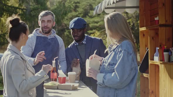 Young people eating fast food near food booth